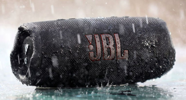 اسپیکر JBL charge 5 که قابلیت ضد آب بودن آن را نمایش می دهد